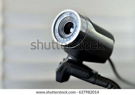 Macro photography of a wired web camera for stationary computers and laptops. A web camera image of a cylindrical shape lying on the computer surface. Focus on the camera lens