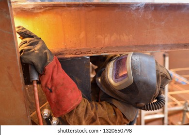 Macro pic of maintenance welder wearing red safety glove welding helmet with power air purifying respirator while performing welding a difficult task condition to protect from the toxic fume   - Powered by Shutterstock