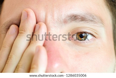 a macro picture of an eye while the other eye  covered by the caucasian male model's hand