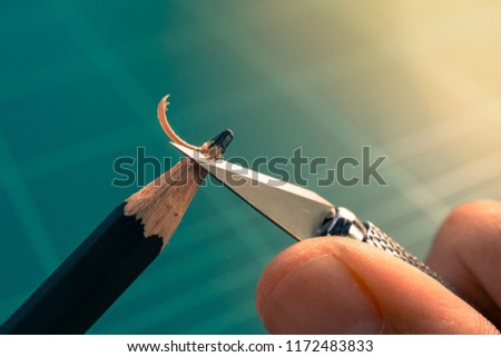 Macro picture of hand sharpening blunt pencil with art knife on green cutting mat. trying concept