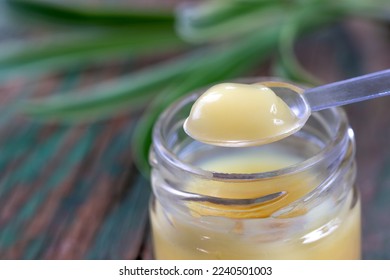 Macro royal jelly in the spoon above the pot - Shutterstock ID 2240501003