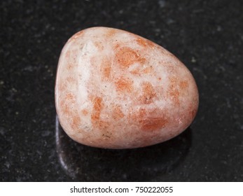 macro shooting of natural mineral rock specimen - polished sunstone (heliolite) gem stone on dark granite background from USA - Shutterstock ID 750222055