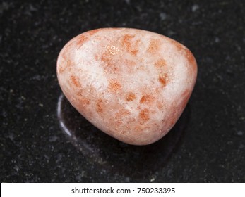 macro shooting of natural mineral rock specimen - tumbled sunstone (heliolite) gem stone on dark granite background from USA - Shutterstock ID 750233395