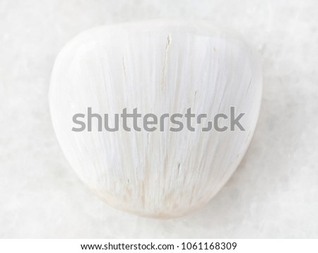macro shooting of natural mineral rock specimen - tumbled Scolecite gemstone on white marble background from Pune region, India