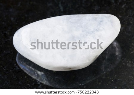 macro shooting of natural mineral rock specimen - pebble of white moonstone (adularia) gemstone on dark granite background Imagine de stoc © 