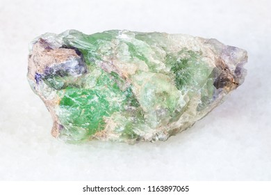 macro shooting of natural mineral - rough green Beryl, Chrysoberyl, Alexandrite gemstone on white marble from Ural Mountains