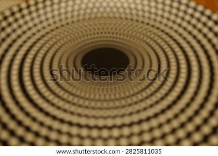 Macro shot of an abstract geometric pattern featuring hypnotic concentric circles and black and white dots, creating an optical illusion effect.