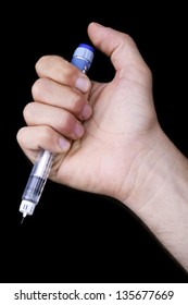 A Macro Shot Of An Adult Man's Hand Holding A Syringe Full Of Penicillin. Isolated On Black Background.