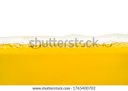 Macro shot of beer in a glass with visible foam and bubbles, isolated on a white background with a clipping path, copy space at the top.