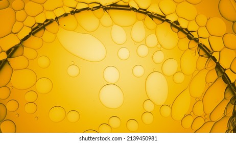 Macro shot of big clear bubble over oil drops against yellow background | Macro shot of body care cream ingredients for its commercial