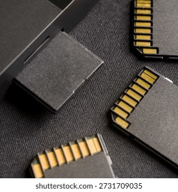 Macro shot of black SD memory card inserted into reader slot with spare cards nearby on dark textured surface. Data storage concept for photography. Photo
