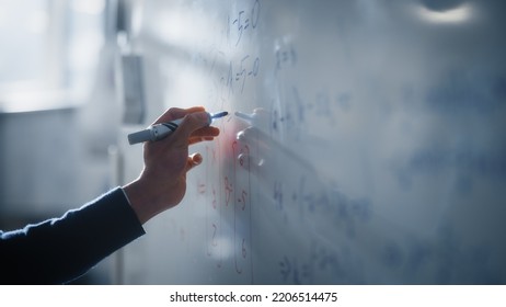 Macro Shot Of A Blue Marker Pen Being Held With A Hand. Teacher Writing Equations On A Whiteboard With Mathematical Formulas. Higher Education In University Of Technology Concept.