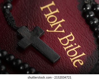 Macro shot. The book of the Holy Bible with a golden inscription and a Catholic cross on the rosary. Symbols of spirituality, Catholicism. Prayer, meditation, humility, love.