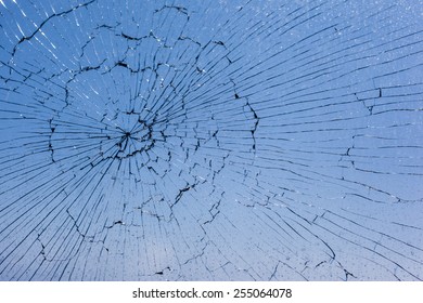 macro shot of a broken glass window against the blue sky
