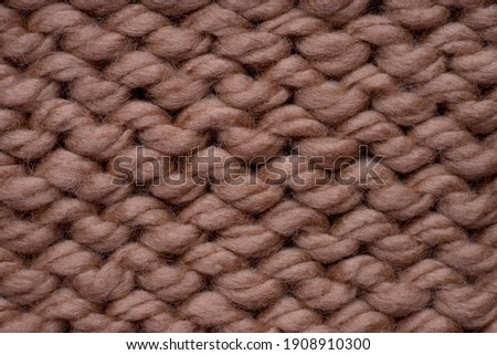 Macro shot of brown woolen knitted fabric texture.