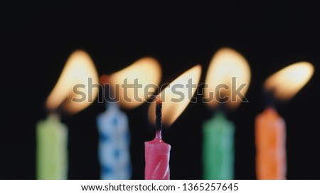Macro Shot Of Burning Colorful Birthday Cake Candles With Flickering Flames On Black Background.