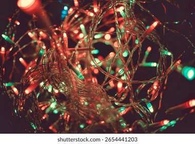 A macro shot captures a dense tangle of thin wires and small LED bulbs emitting red and green light, creating a festive and blurry background.