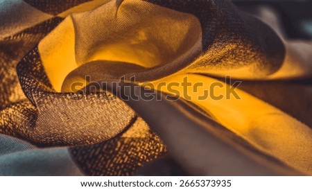 A macro shot capturing the mesmerizing texture of fabric with its intricate weave and golden hues. The play of light and shadow on the folds accentuates the material's soft and smooth texture