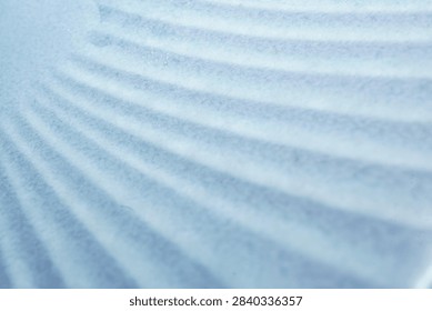 A macro shot capturing soft, repeating sinusoidal shadows across a pale surface. These gentle ripples create a calming, rhythmic pattern, suggesting natural light filtering through waves or fabric folds. Perfect for abstract backgrounds and textures.