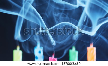 Macro shot of colorful birthday cake candles extinguished and smoking after being blown out.