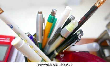 Macro shot of a container full of pens and pencils on an office desk