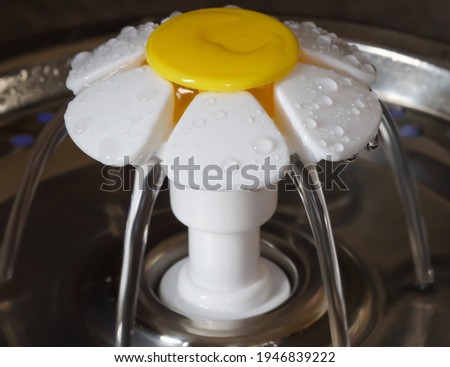A macro shot of a daisy cat water fountain in operation with water flowing 