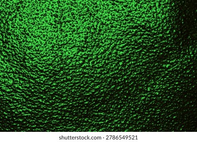 Macro shot of dark green bumpy glass texture with backlighting. Close up abstract background of emerald stained glass window or rough patterned bottle surface.