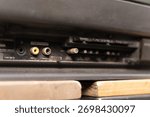 Macro shot of the dusty back panel of a vintage television, showing the yellow video and white audio RCA input ports. Obsolete technology concept.