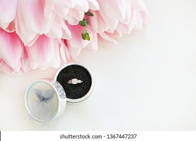 Macro Shot Of Expensive White Gold Diamond Ring And Beautiful Tender Pink Tulips. Top View Composition With Engagement Ring And Flower Petals. Feminine Wedding Background With Copy Space For Text.