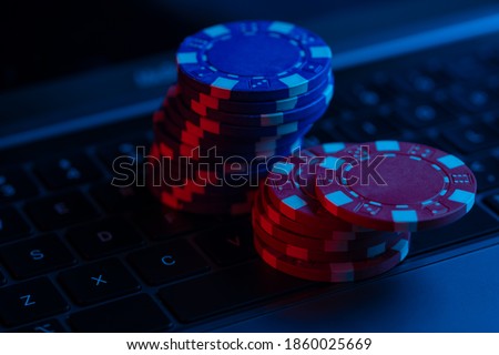 Macro shot of gambling poker chips on laptop keyboard. Concept of online gaming.