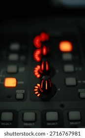 Macro shot of glowing red knobs and buttons on a professional sound mixing board, perfect for music production and studio themes.