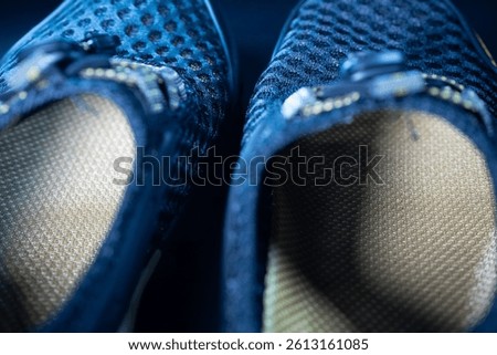 A macro shot of the inside of a black mesh shoe, highlighting the textured insole and breathable outer material. Offers a detailed look at the comfort and construction.