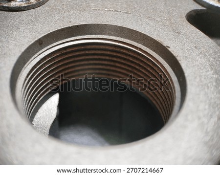 Macro shot of internal screw threads in a grey metal component, showing fine machining detail and slight rust or oxidation on the threads inside the industrial metal bore.