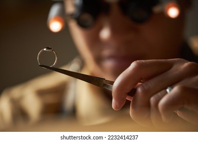 Macro shot of jeweler holding golden ring with tweezers in artisanal workshop - Powered by Shutterstock