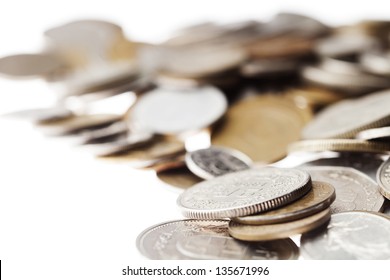 Macro shot of a large quantity of unrecognizable coins (except for one that appears to be Swiss) stacked in chaos over white background. Very shallow depth of field.