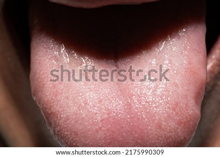 A macro shot of a man with white facial hair's tongue. 