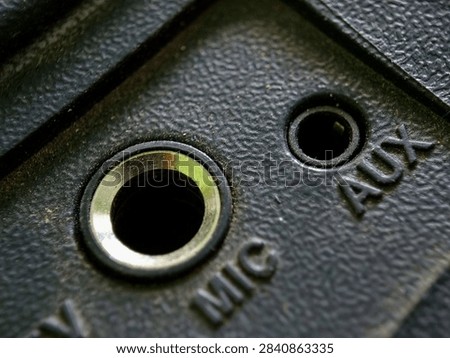 Macro shot of MIC input socket and AUX audio port on black textured electronic panel
