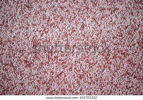 Macro shot of mixed chemical, artificial nitrogen\
plant fertilizer granules in factory. Big heaps of mineral pellets\
creating abstract textures, patterns. Minerals used in agriculture,\
farms, fields
