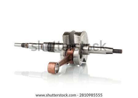 Macro shot of a new motorcycle engine crankshaft assembly with a connecting rod isolated on a white background. High-quality steel crankshaft replacement part for scooter, moped, or chainsaw motor overhaul. High-key studio technical product photography.