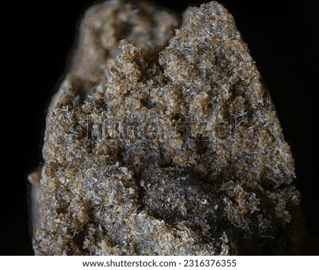A macro shot of a piece of hashish with fine detail on a black background
