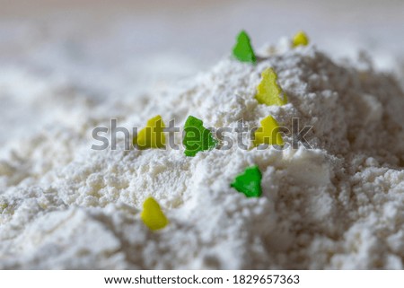 Macro shot of a pile flour with little green sugar trees on it