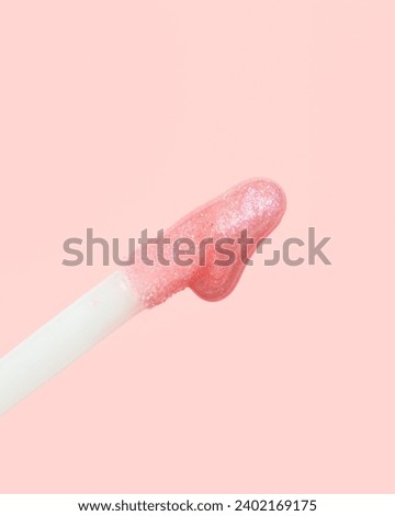 Macro shot of pink glitter lipgloss on doe foot applicator with lipgloss background 