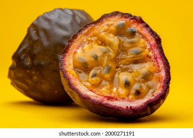 Macro shot with pulp flesh and black seeds of Maracuja or Brazilian tropical passion fruit. Studio still life against a yellow background