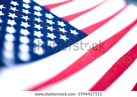 A macro shot with selective focus of a small handheld American flag on coarse fabric.