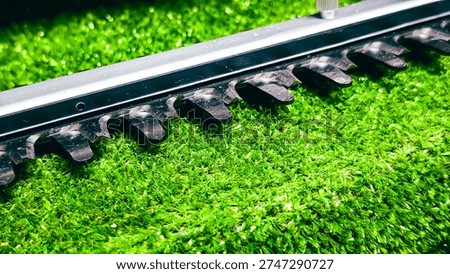 Macro shot of sharp hedge trimmer blades over artificial green grass