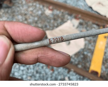 A macro shot of a single E7018 low-hydrogen carbon steel welding electrode. The image clearly shows the 