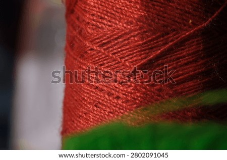 Macro shot of a spool of dark red sewing thread showing detailed fiber texture.