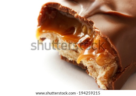 Macro shot of tasty chocolate bar. Delicious caramel cream and peanuts inside.White background.