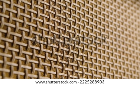 Macro shot of the texture of a fibrous threads, checkered structure surface. Beige and brown threads are intertwined in a checkered pattern. Cover of an old radio receiver. Canvas, fabric, jute weave.