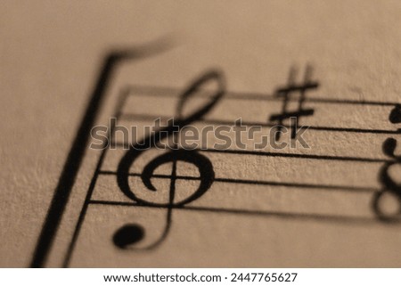 Macro shot of a treble clef and sharp symbol on sheet music, highlighting musical details.
